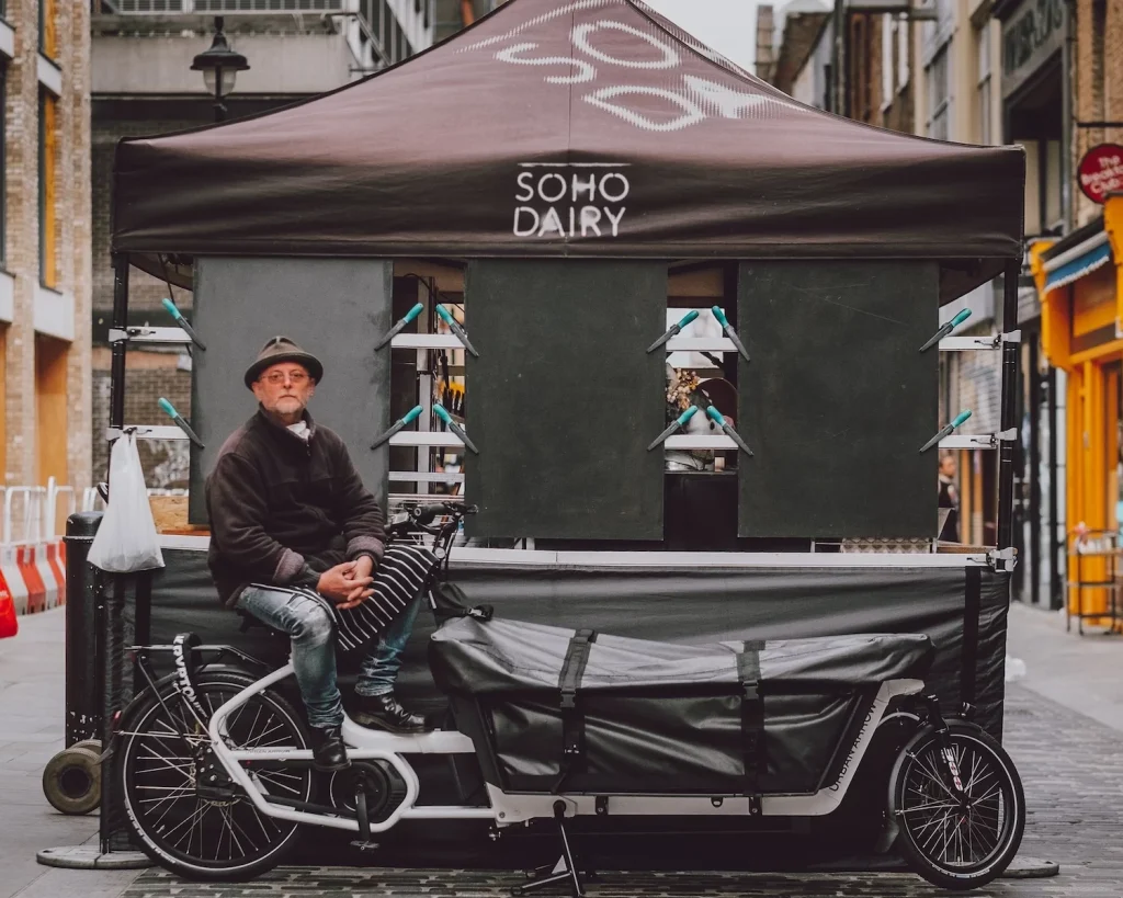 An image showing Soho Dairy founder Robin sitting on his electric cargo delivery bike at the Soho Dairy stall